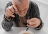 Silent Sarcopenia — The Preventable Slide Elderly man focusing intently on a spoon while preparing to eat