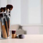 A collection of makeup brushes in a glass container on a table