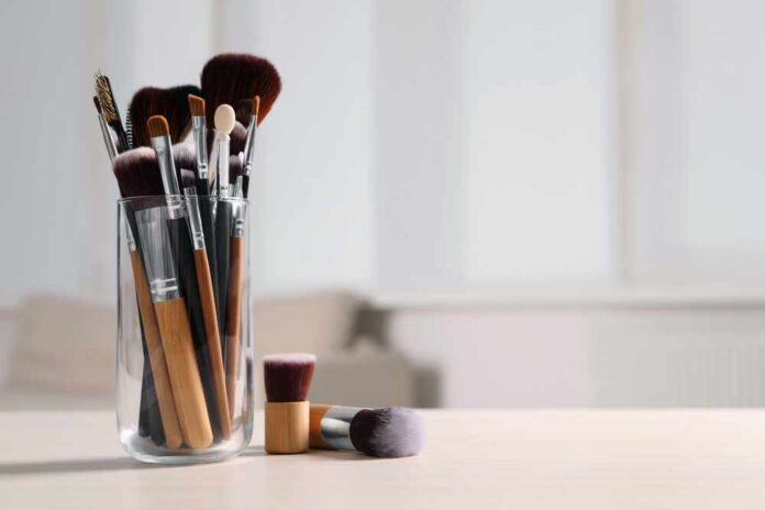 Set,Of,Professional,Brushes,On,Wooden,Table,Indoors,,Space,For A collection of makeup brushes in a glass container on a table