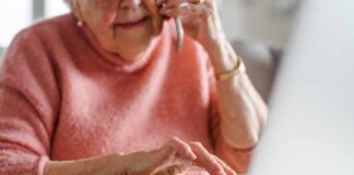 Elderly woman on a phone call while using a laptop