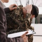 Soldier in camouflage sits with head in hands during counseling session