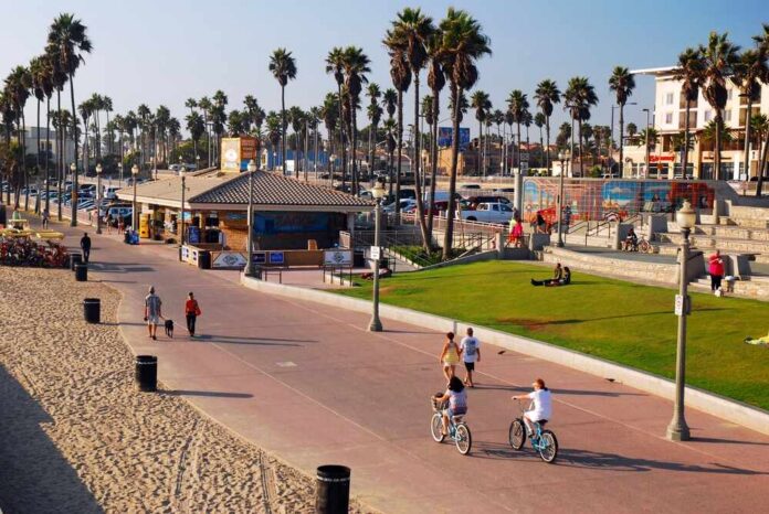 Huntington,Beach,,Ca,,Usa,September,25,People,Enjoy,A,Sunny People walking and biking along a beach promenade with palm trees