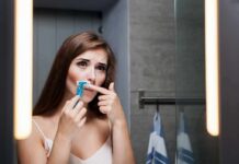 Woman shaving upper lip in bathroom mirror