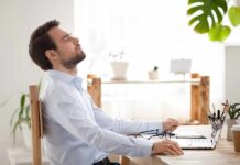 The Science of Silence: How It Rewires Your Brain Man relaxing at desk with eyes closed beside laptop
