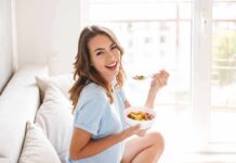 Woman sitting on a couch eating a bowl of fruit salad