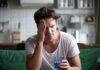 Man with headache holding a glass of water