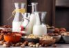 Glass bottles of milk surrounded by assorted nuts in bowls