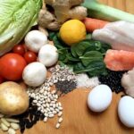 Assorted fresh foods including vegetables, grains, eggs, fish, and chicken