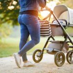 Person pushing a baby stroller on a park path