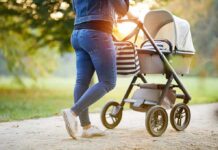 Person pushing a baby stroller on a park path
