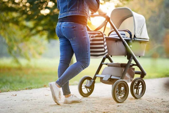Person pushing a baby stroller on a park path