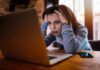 How Can We Protect Mental Health in a Remote Work Era? Woman holding head while looking at laptop