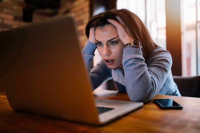 shutterstock_1047662398 Woman holding head while looking at laptop