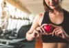 Woman in sportswear holding a red heart-shaped object at the gym