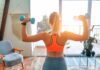 Woman lifting dumbbells at home gym near window