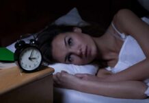 Sleep Aid Fix — Without Melatonin Woman lying awake in bed beside an alarm clock