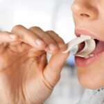 Person placing a piece of chewing gum in their mouth