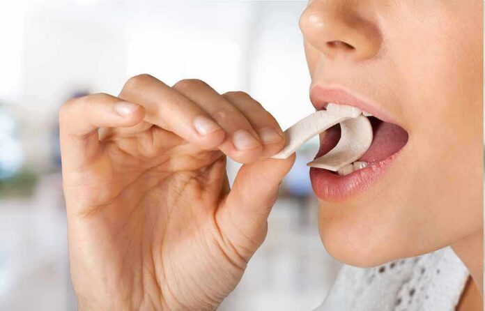 Person placing a piece of chewing gum in their mouth