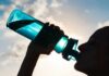Silhouette person drinking from a blue water bottle