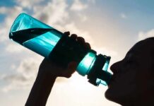 Silhouette person drinking from a blue water bottle