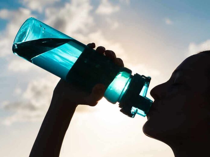 shutterstock_376704928 Silhouette person drinking from a blue water bottle