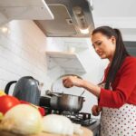 Woman in red sweater cooking at stove with a grimace