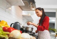 The Healthiest Vegetables for Men vs. Women Woman in red sweater cooking at stove with a grimace
