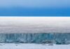 Hidden Penguins Upend Conservation Maps Ice cliff along a polar glacier under a blue sky