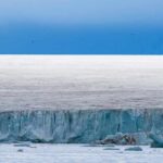 Ice cliff along a polar glacier under a blue sky