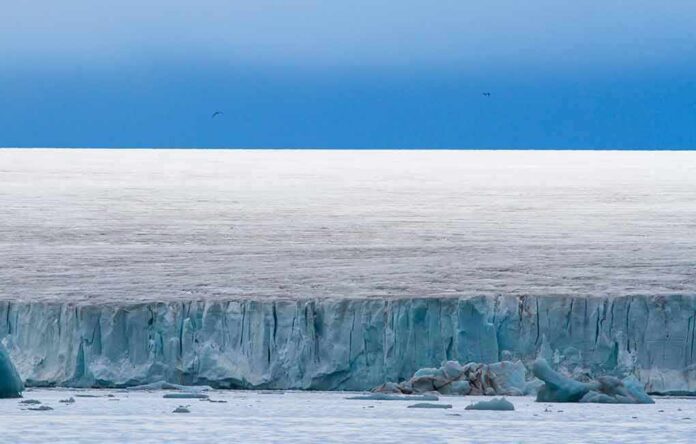 Ice cliff along a polar glacier under a blue sky
