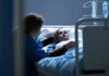 Cancer Diagnosis Triggers Sudden Stroke Spike Patient in hospital bed with visitor holding their hand
