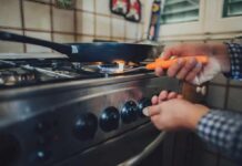 Health Benefits of Electric Kitchens Person lighting a gas stove under a frying pan