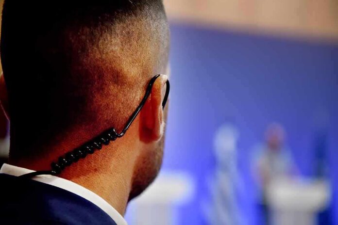 Security guard with earpiece watching a blurred event stage