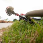 Road bicycle lying on grass beside a rural path