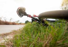 Road bicycle lying on grass beside a rural path