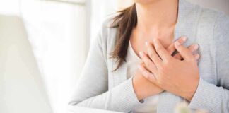 person clutching chest with both hands at a desk