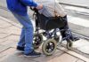 Caregiver pushing person in wheelchair over curb