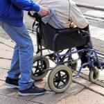 Caregiver pushing person in wheelchair over curb