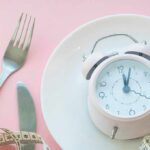 Weekend Brunch & Late Dinners – Cardiovascular Alarm Bells Pink alarm clock on a white plate with fork, knife, and measuring tape
