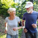 older couple jogging together in a sunny park