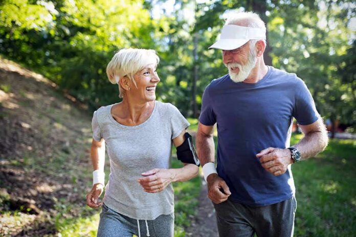 older couple jogging together in a sunny park