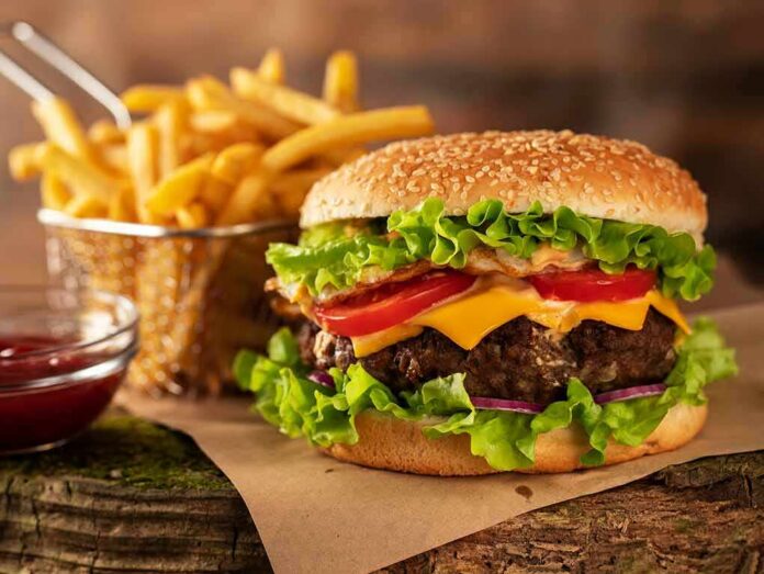 shutterstock_1399168025 Cheeseburger with fries on rustic surface