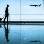 Traveler with rolling suitcase in airport terminal
