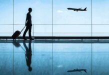 Traveler with rolling suitcase in airport terminal