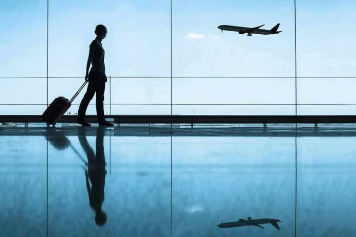 Traveler with rolling suitcase in airport terminal