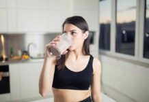 Woman in sportswear drinking a smoothie in a kitchen