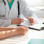 Doctor discusses medical notes with patient at a desk