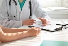 Doctor discusses medical notes with patient at a desk