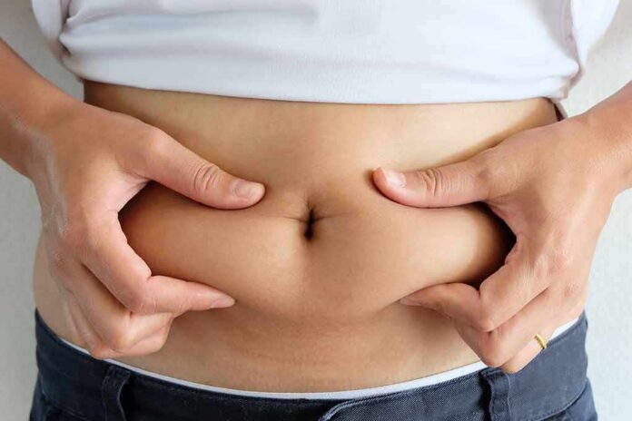 shutterstock_510854272 person pinching belly fat at the waist