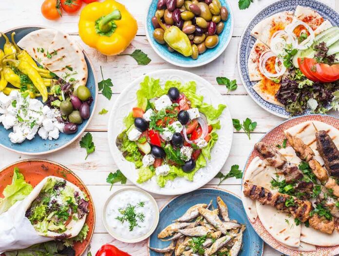 Greek meze spread with salad, olives, pita, and grilled skewers